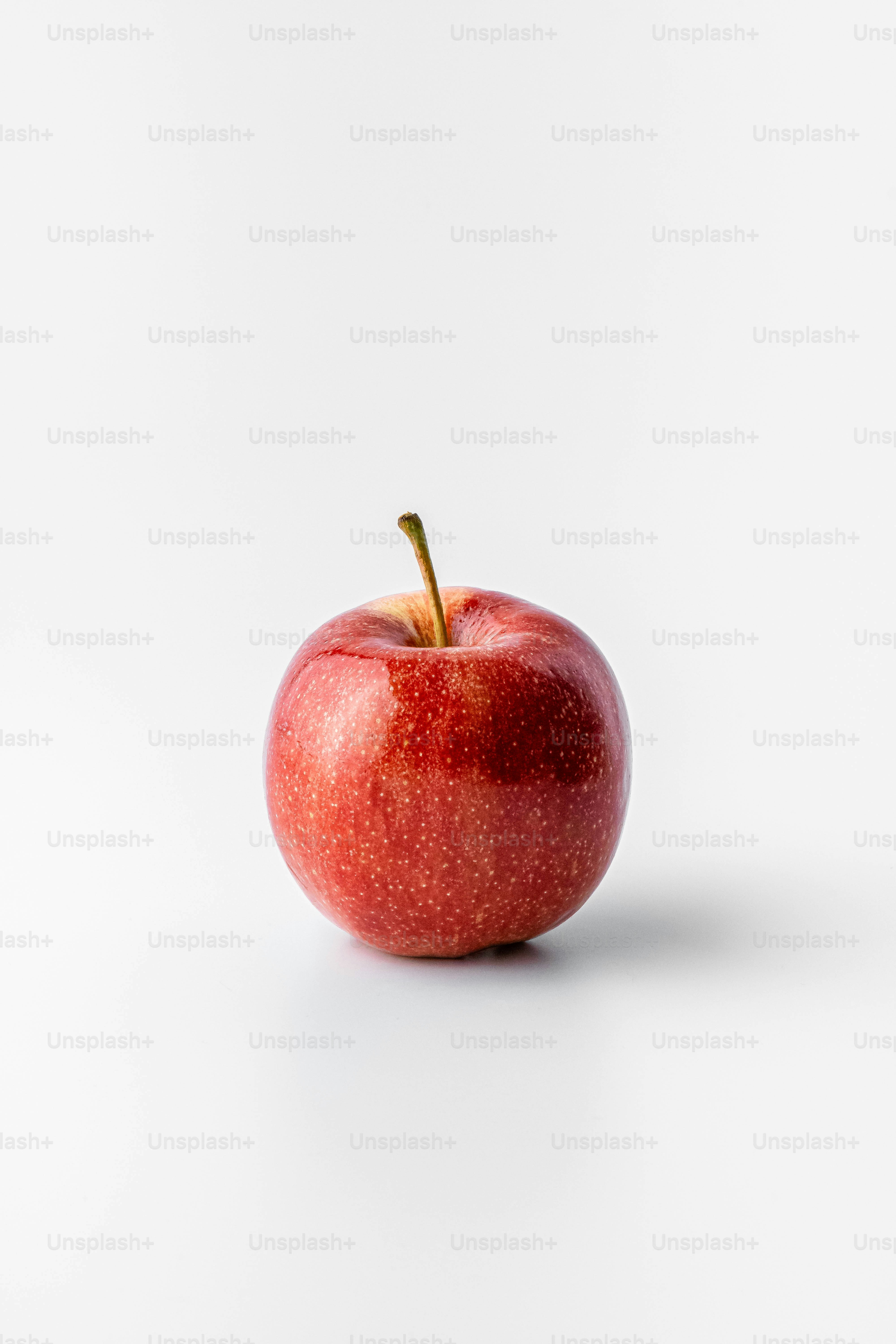 A red apple sitting on top of a white table